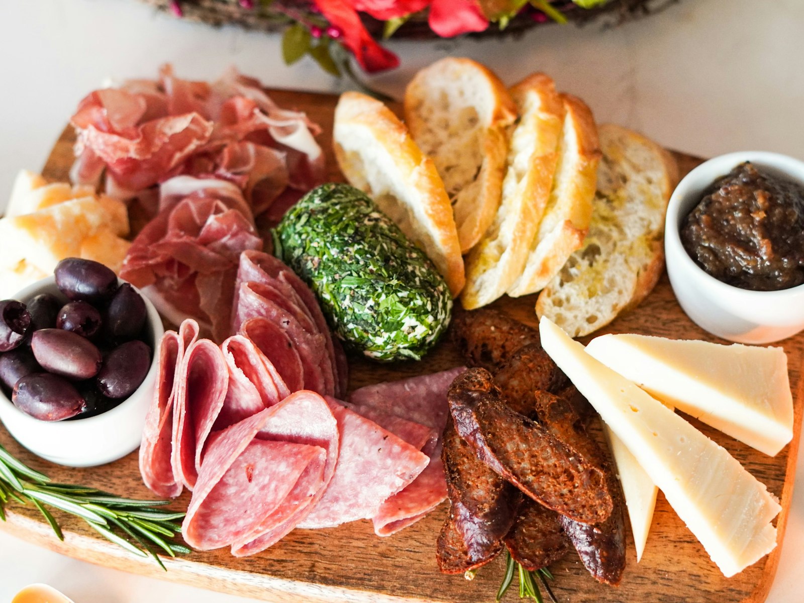 Premium charcuterie board with prosciutto, salami, aged cheese, olives, bread and fresh rosemary