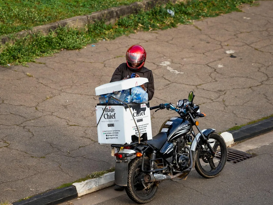 A delivery rider on a motorbike with an order box strapped on the back