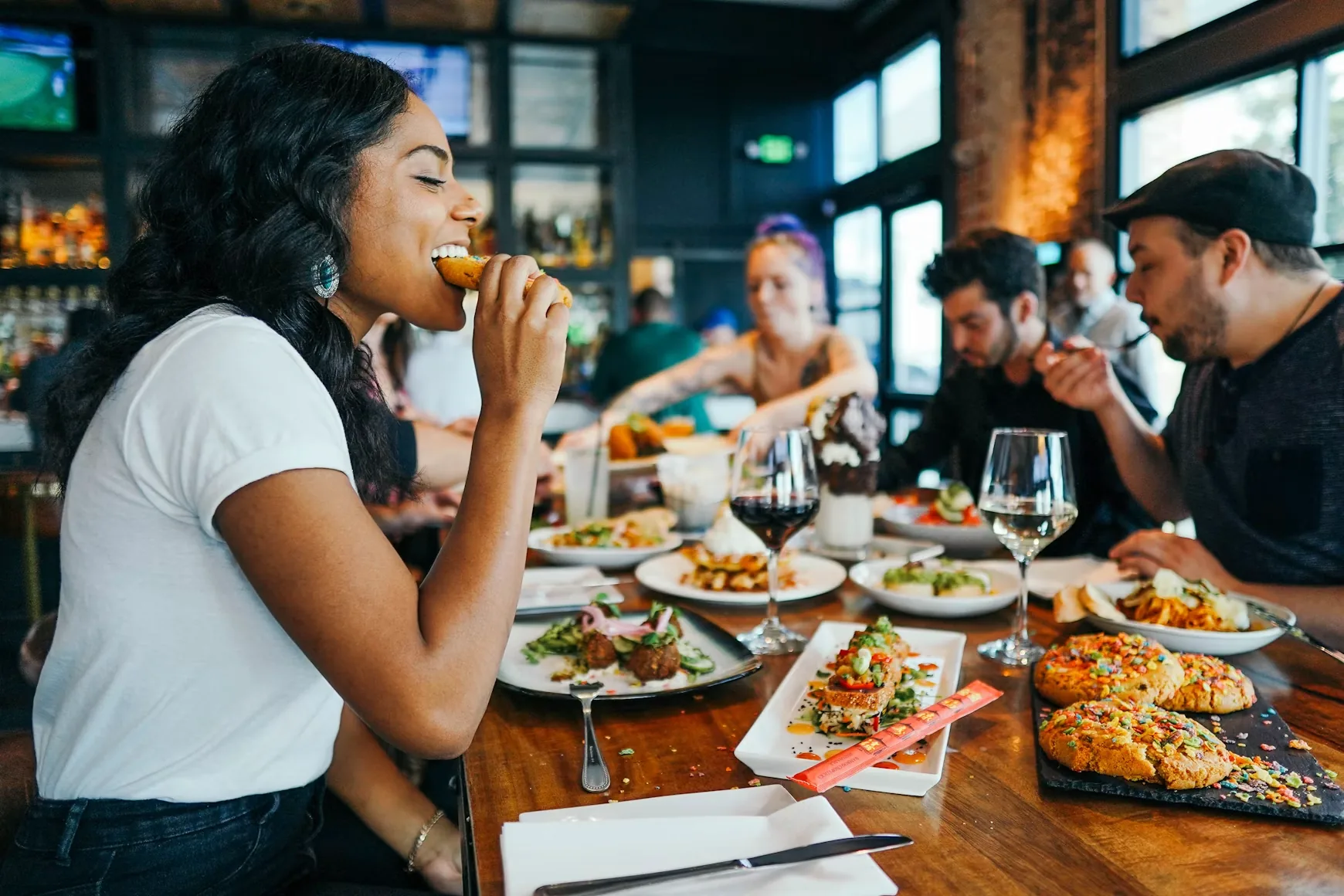 Friends sharing plates at a long restaurant table